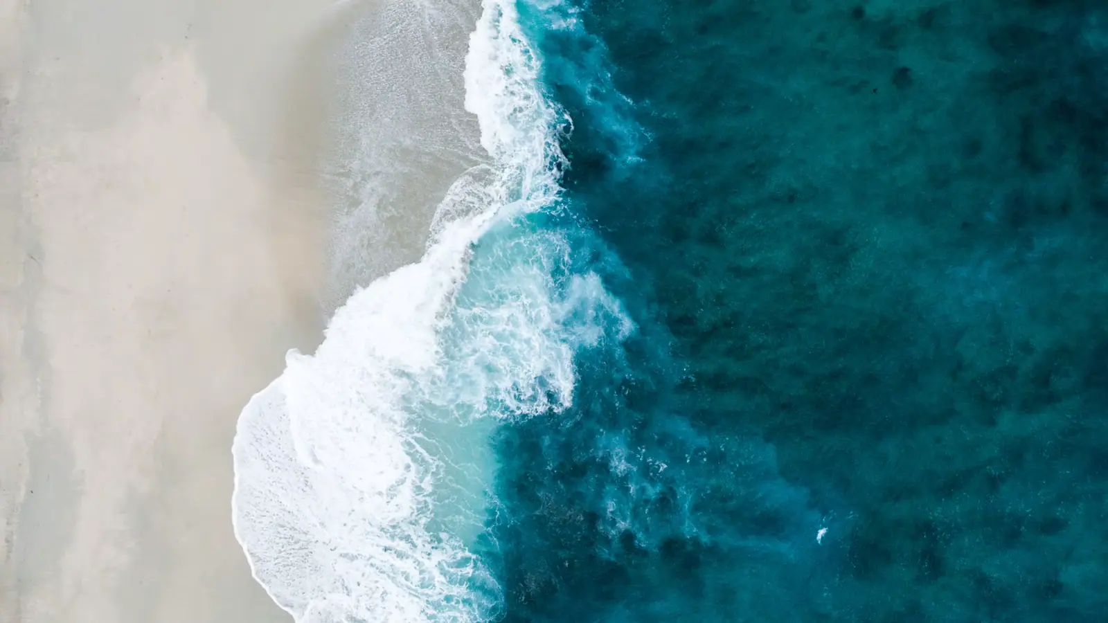 Heavy surf breaking on an empty, rocky windward beach under a bright sky